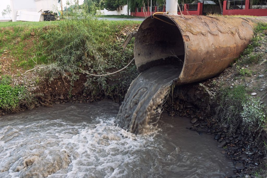 A picture of a drain pipe disposing of water into a river