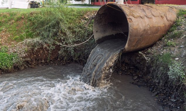 A picture of a drain pipe disposing of water into a river